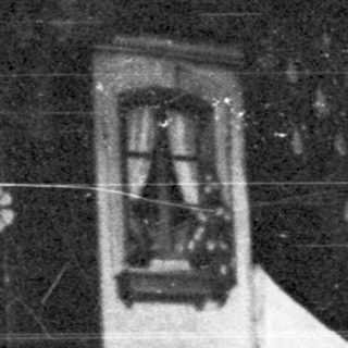 Here's a brief summary of the image: Person stands near a building with an arched doorway.