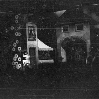 Here's a brief summary of the image: A person stands near a building with an arched doorway.