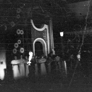 Night scene; figures, lanterns, and a decorated structure are visible.
