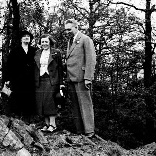 Three people stand on rocks in a wooded area.