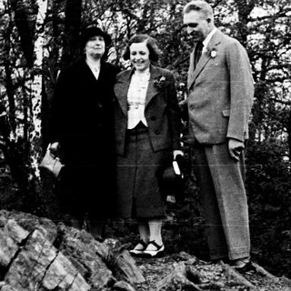 Three people stand on rocks in a wooded area.