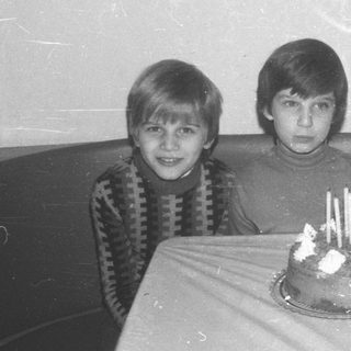 Three boys pose with a birthday cake.
