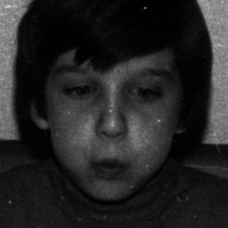 Boy sits at a table with a birthday cake.