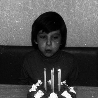 Boy sits at a table with a birthday cake.