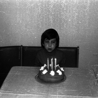 Boy sits at a table with a birthday cake.