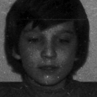 A child sits before a cake with lit candles.