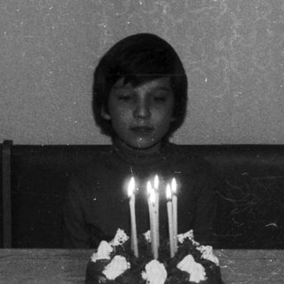 A child sits before a cake with lit candles.