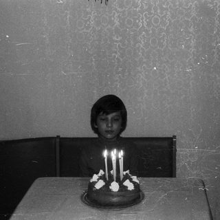 A child sits before a cake with lit candles.