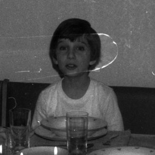 Boy sits at a formally set table with candles.