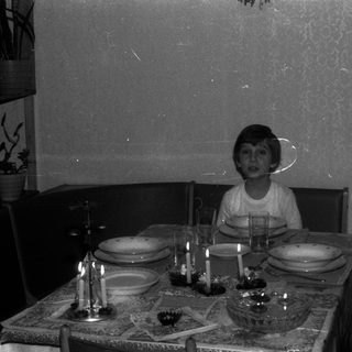 Boy sits at a formally set table with candles.