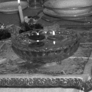 Table setting with candles, plates, and glasses in a room.