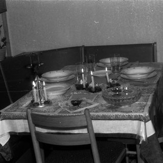 Table setting with candles, plates, and glasses in a room.