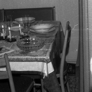 Table setting with candles, plates, and glasses in a room.