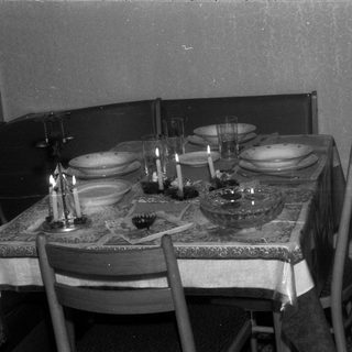 Table setting with candles, plates, and glasses in a room.