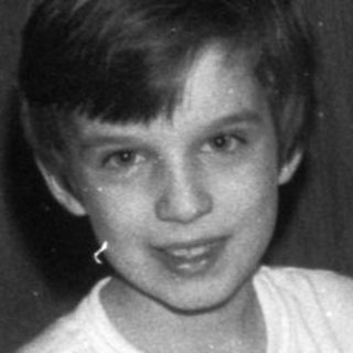 Boy sitting with a stuffed animal and toys.