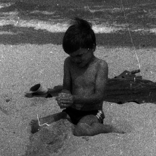 Boy playing on a sandy beach near the ocean.