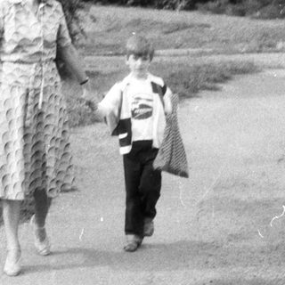 Woman and child walk along a road, viewed from behind.