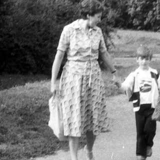 Woman and child walk along a road, viewed from behind.