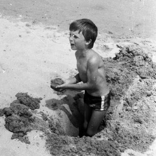 Boy playing in a sand hole at the beach.