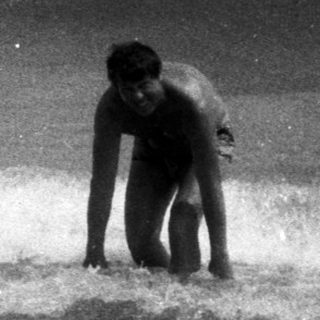 Person wading in ocean waves, black and white photograph.
