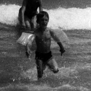 Child playing in the ocean waves on a sunny day.