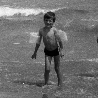 Black and white image of a child and woman on a beach.