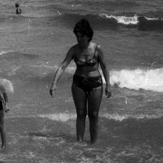 Black and white image of a child and woman on a beach.