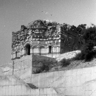 Ruined building on a hill, with a boy in the foreground.