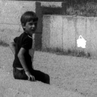 Ruined building on a hill, with a boy in the foreground.