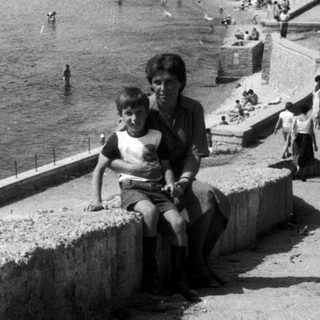 Black and white image of a beach with people swimming.
