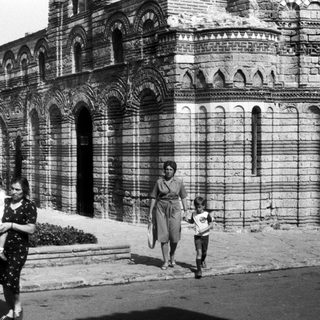 Black and white image of people near an old building.