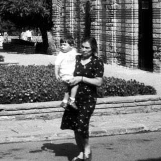 Black and white image of people near an old building.