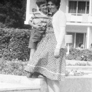 Woman carrying a child in front of a building.