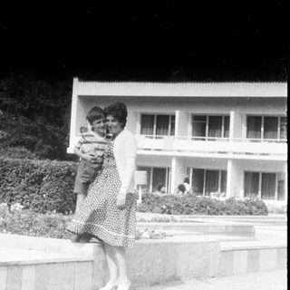 Woman carrying a child in front of a building.