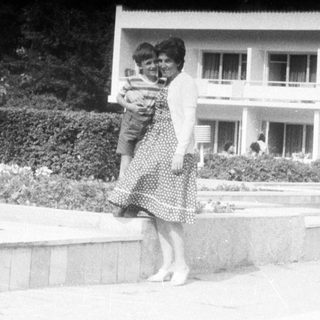Woman carrying a child in front of a building.