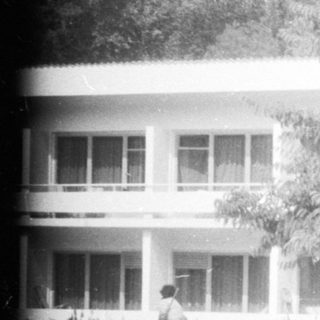 Black and white photo depicts a building and landscaping.