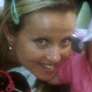 Woman and baby in a stroller on a paved street.