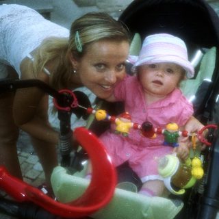Woman and baby in a stroller on a paved street.