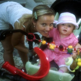 Woman and baby in a stroller on a paved street.