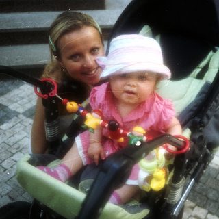 Baby in stroller with a smiling woman nearby.