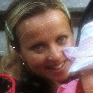 Baby in stroller with a smiling woman nearby.