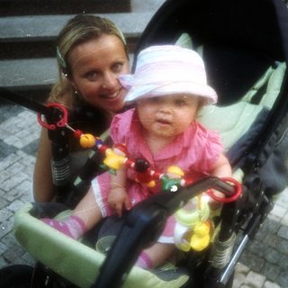 Baby in stroller with a smiling woman nearby.