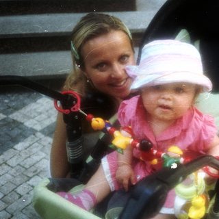 Baby in stroller with a smiling woman nearby.