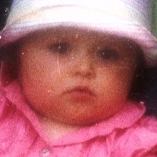 Baby in a stroller with toys, outdoors.