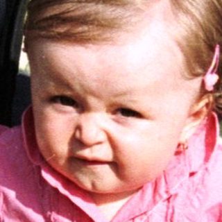 Baby sits in stroller, playing with a toy.