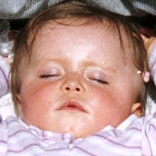 Baby sleeps peacefully in a stroller with toys.