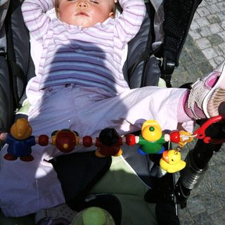 Baby sleeps peacefully in a stroller with toys.