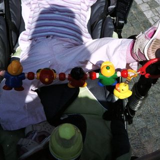 Baby sleeps peacefully in a stroller with toys.