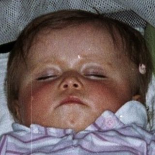 Baby sleeps peacefully in a stroller with a toy.