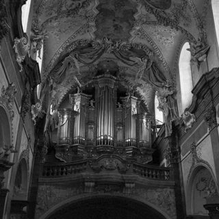 Elaborate pipe organ within a decorated church interior.
